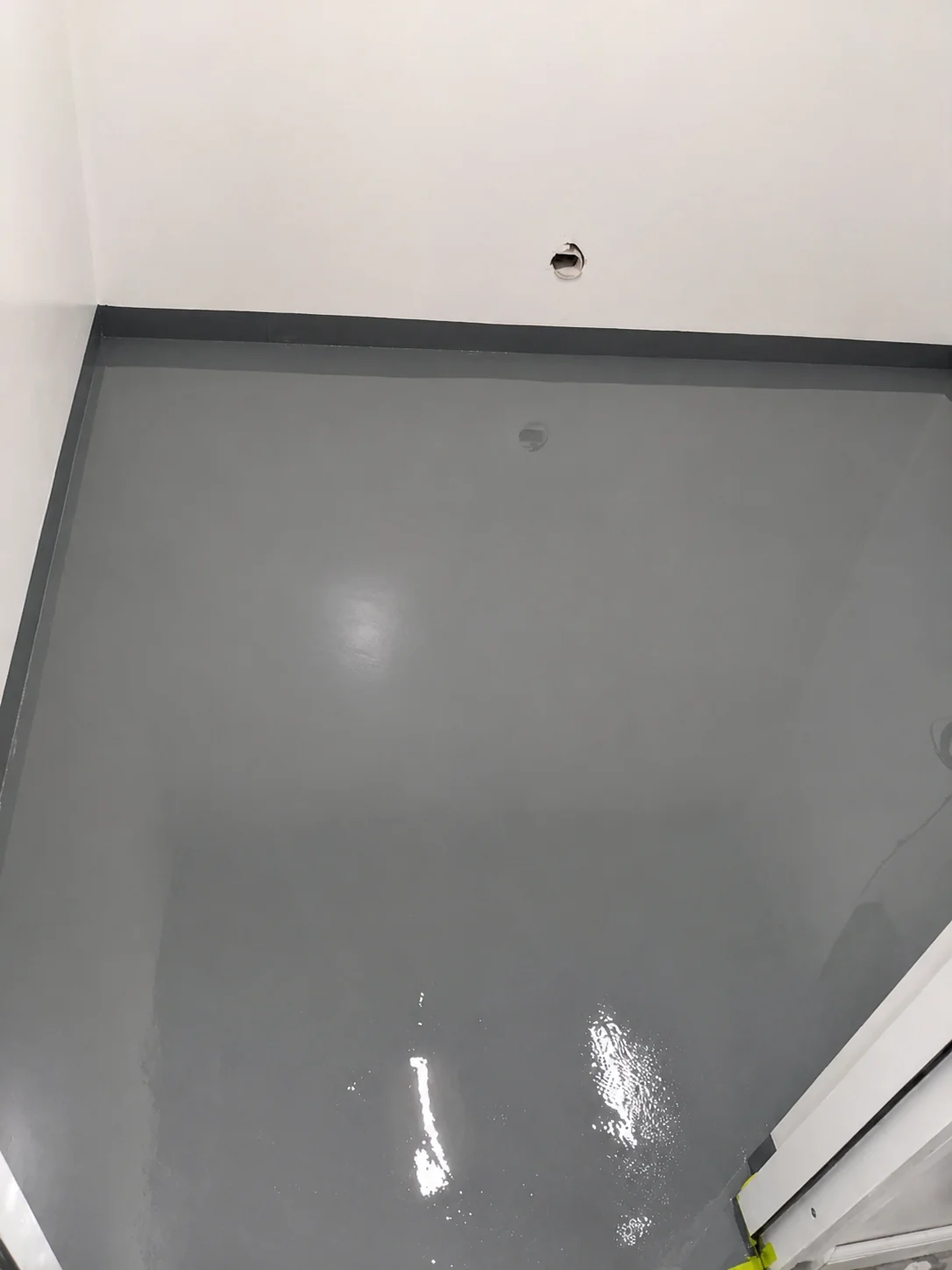 Finished grey ESD epoxy floor with a glossy even surface and a dark coved skirting running along the wall base.