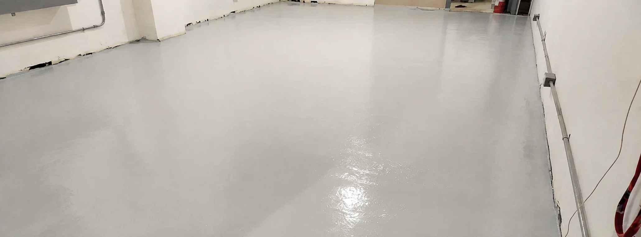 Completed light grey ESD epoxy floor with a smooth satin finish, running the full width of the room to the wall edges.