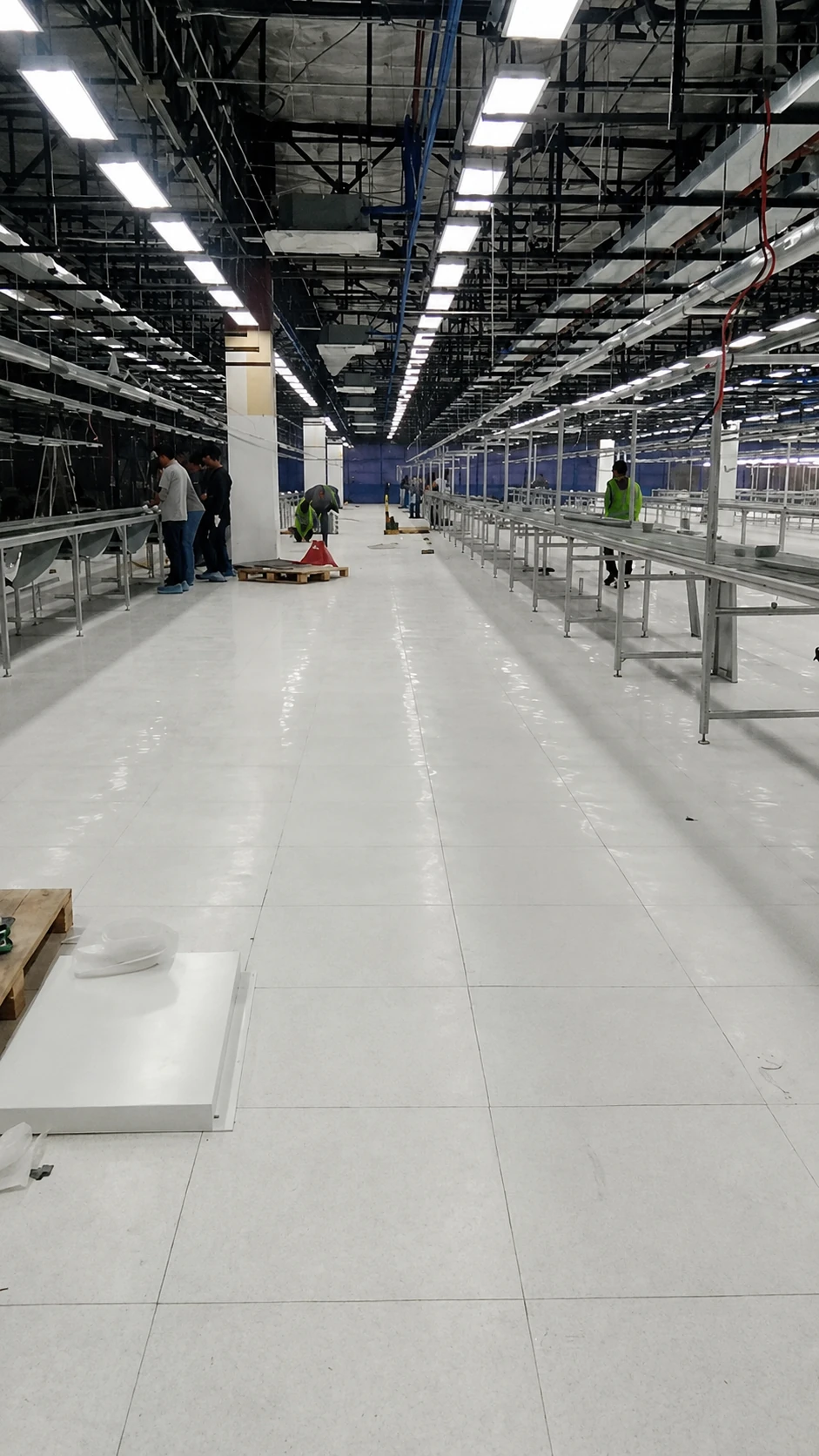White ESD tile floor along an assembly line aisle with workers setting up conveyor stations