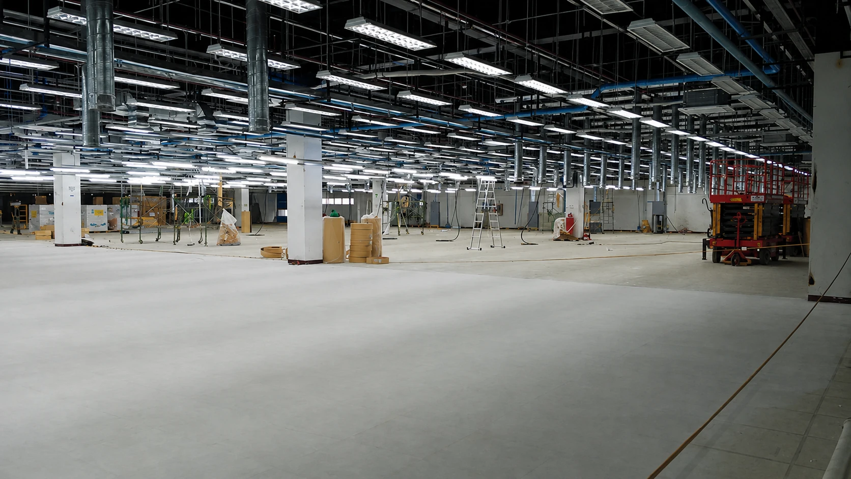 Subfloor preparation in an industrial facility with scissor lift and installation materials on site